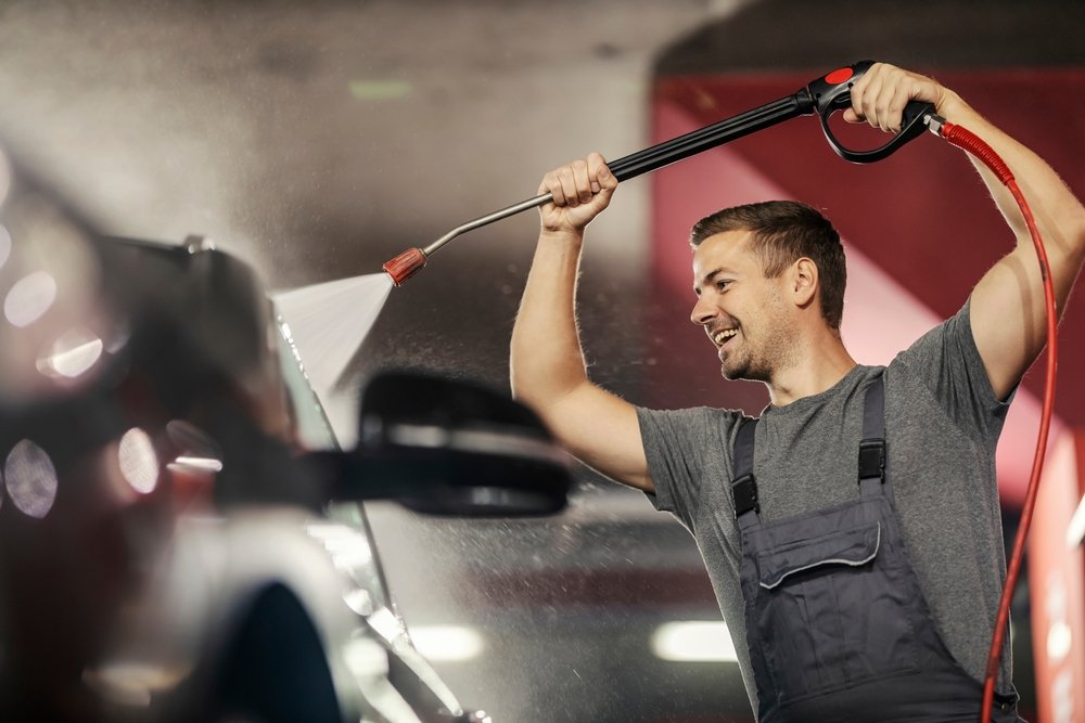 man pressure washing a car